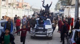 Pejuang Hamas bersenjata melaju pada Minggu (19/1/2025) melewati kerumunan warga Palestina di jalan-jalan Deir al-Balah, Gaza, sambil meneriakkan yel-yel perayaan setelah gencatan senjata yang tertunda mulai berlaku. (REUTERS/Mohammed Salem)