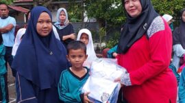 Plt Kepala Sekolah SDN 86 Pekanbaru, Serly Efrita, S. Pd saat menyerahkan seragam kepada salah satu siswa penerima bantuan, Kamis (18/12). Dok. Istimewa