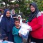 Plt Kepala Sekolah SDN 86 Pekanbaru, Serly Efrita, S. Pd saat menyerahkan seragam kepada salah satu siswa penerima bantuan, Kamis (18/12). Dok. Istimewa